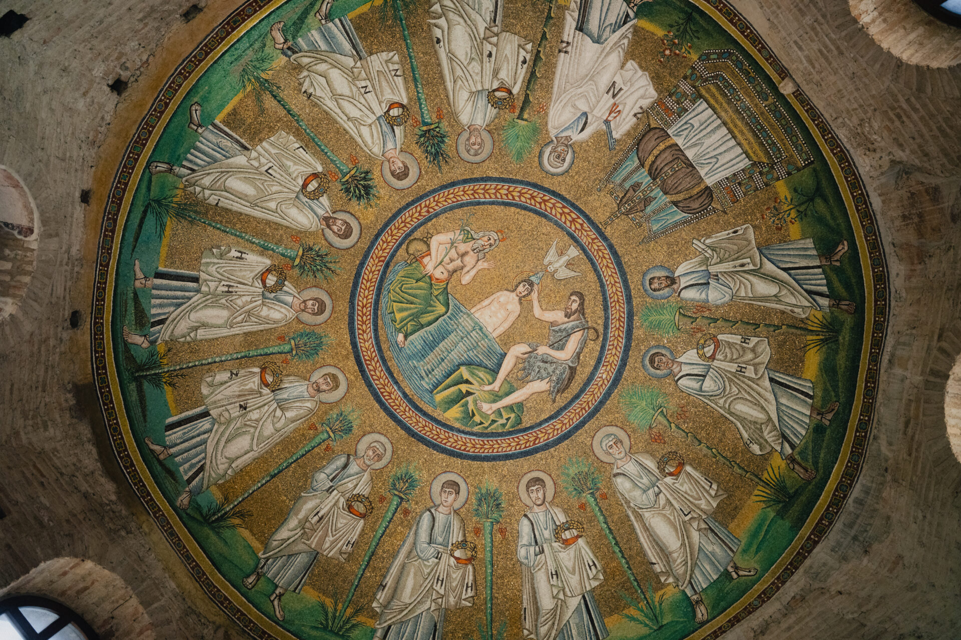 Un soffitto circolare a mosaico raffigurante il battesimo di Gesù, circondato da santi in abiti bianchi, su uno sfondo dorato con dettagli intricati.
