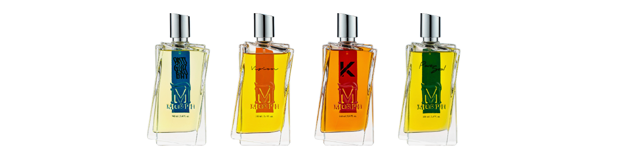 Four glass perfume bottles with silver caps, filled with yellow, orange, deep orange, and green liquid; each has unique labels.