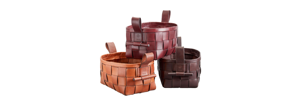 Three woven leather baskets in brown, burgundy, and tan are stacked with handles and rectangular shapes on a plain white background.