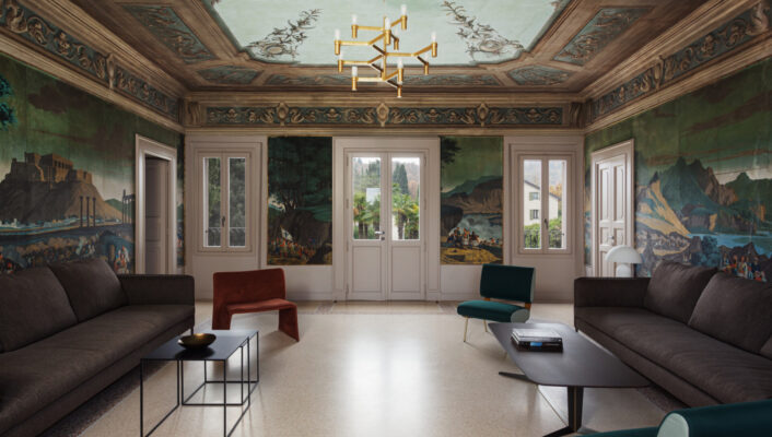 Elegant living room with mural walls, ornate ceiling, two dark sofas, modern tables, accent chairs, big windows, gold chandelier.